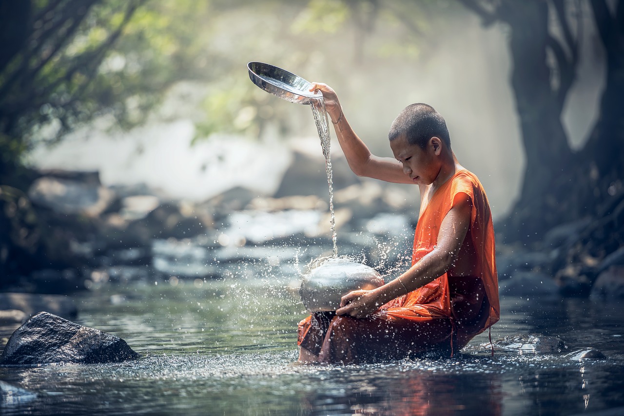Na zdjęciu buddysta leje wodę nad rzeką.